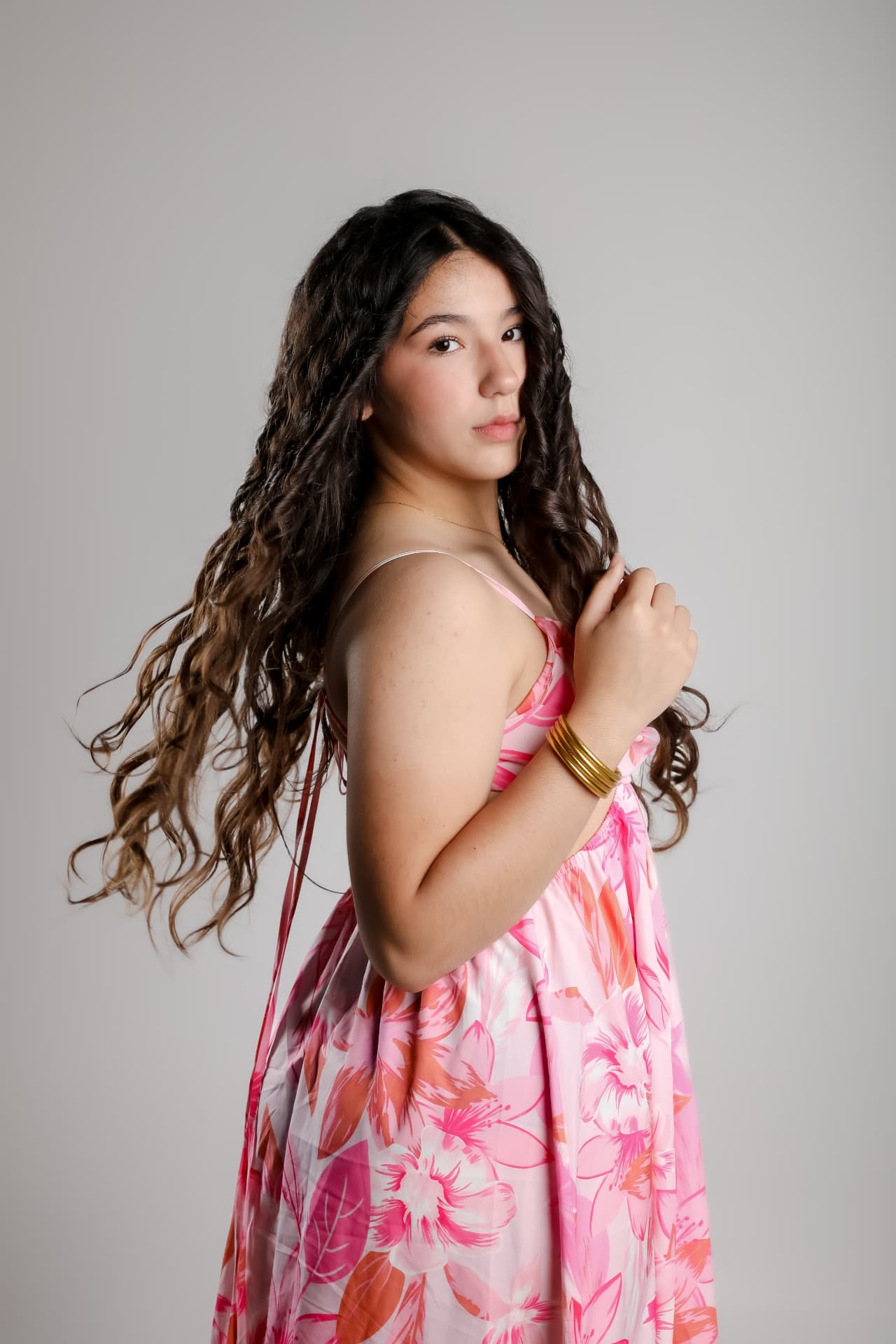 Retrato de joven con vestido floral rosa sobre fondo gris