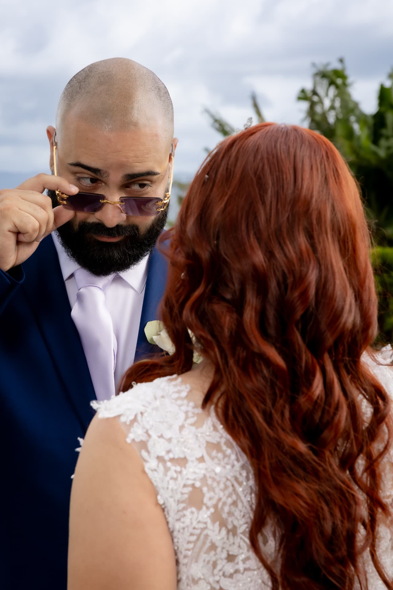 Novio con lentes de sol dorados mirando a la novia de espaldas