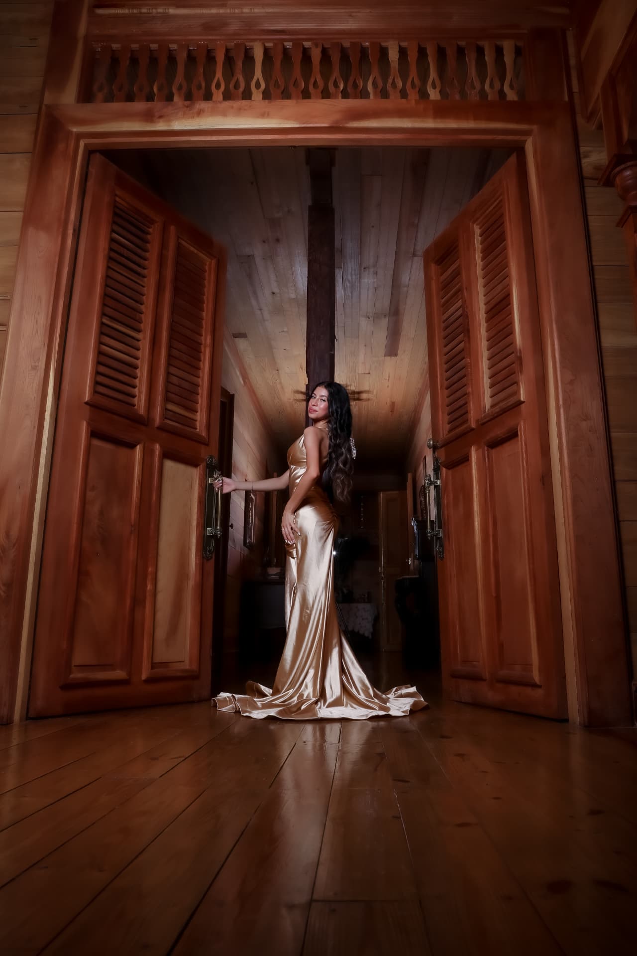 Joven en vestido dorado entre puertas de madera de hacienda