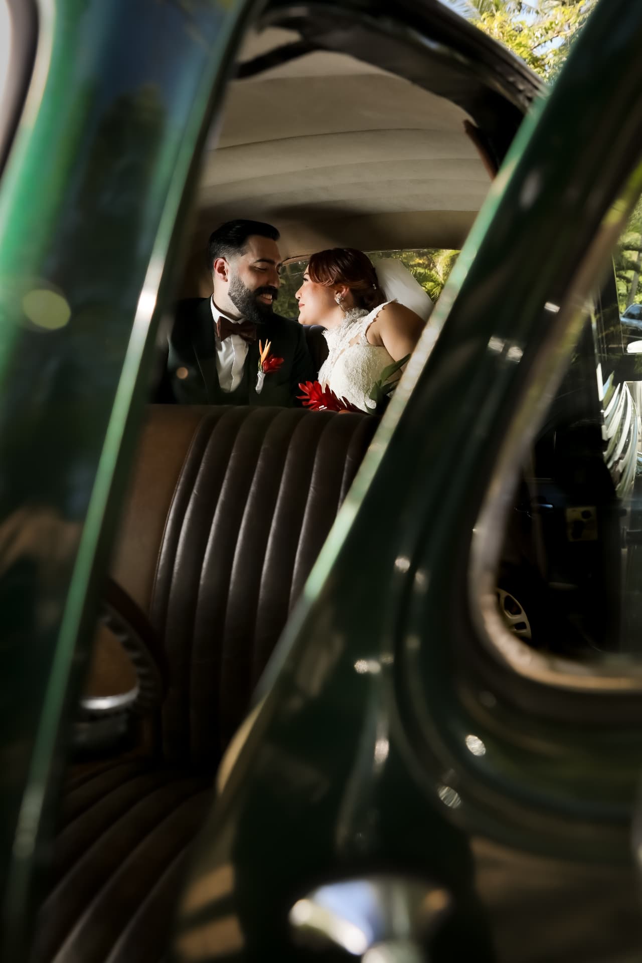 Pareja de novios dentro de un auto clásico mirándose con cariño