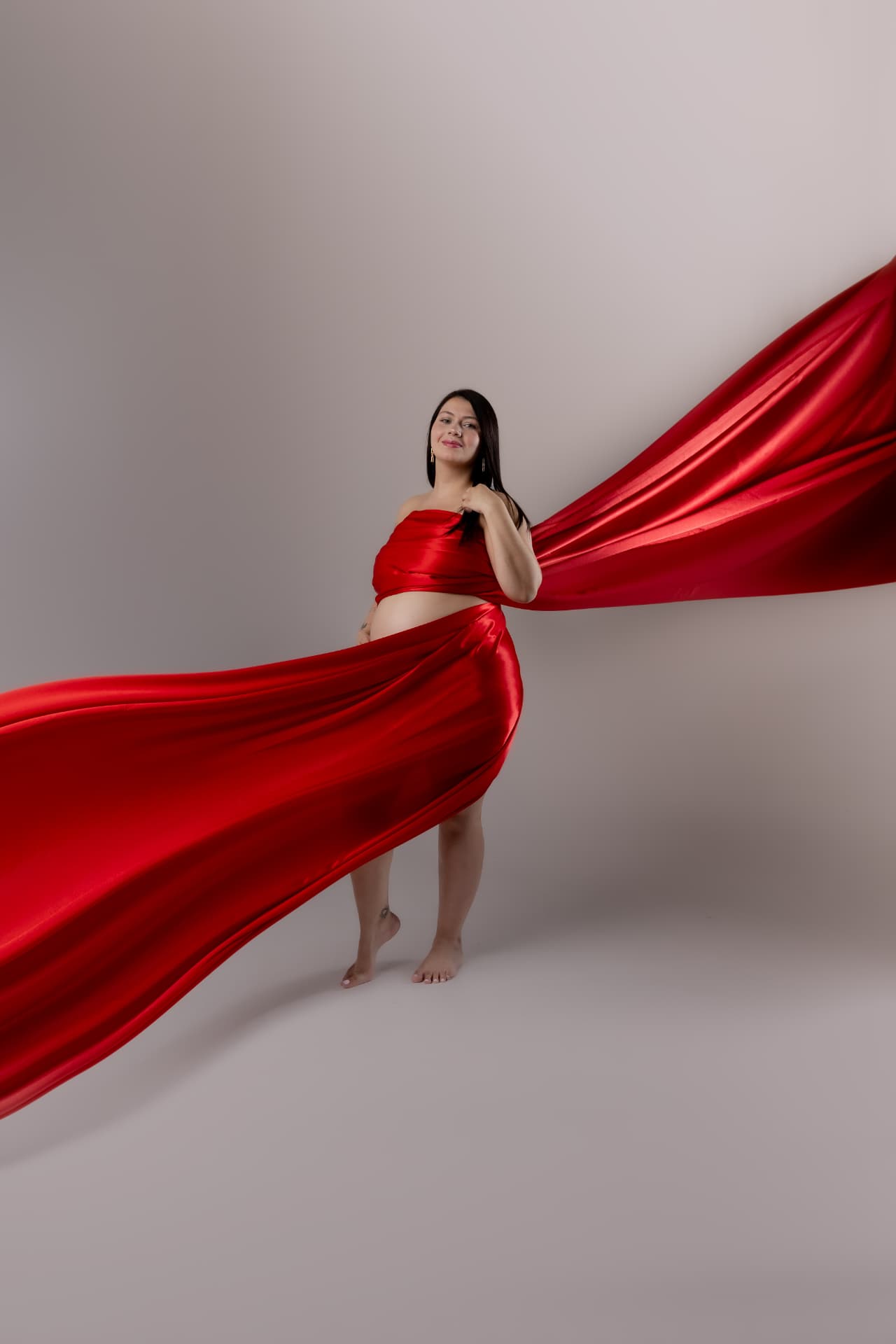 Embarazada con tela roja fluyendo a su alrededor