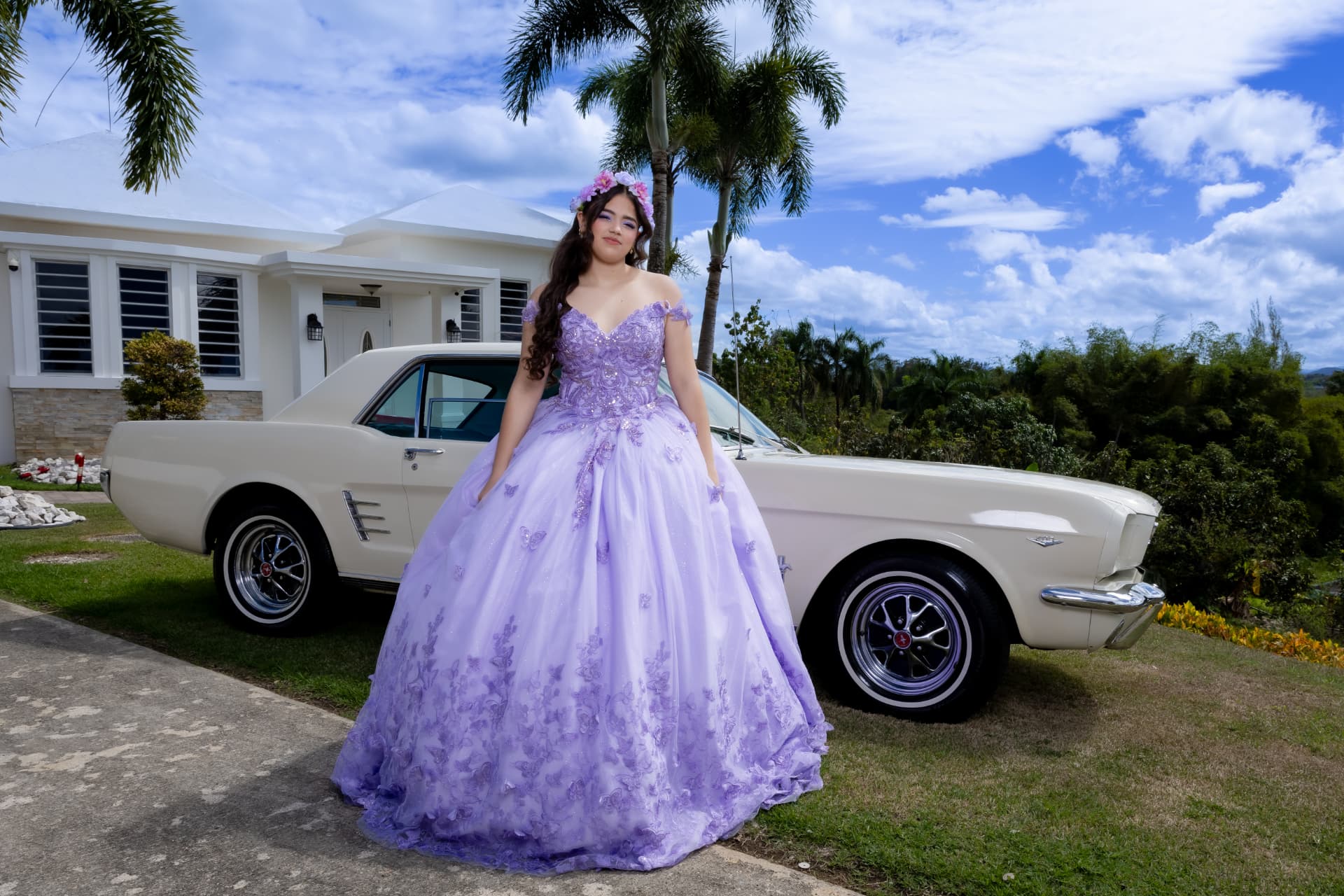 Quinceañera con vestido lila junto a auto clásico blanco