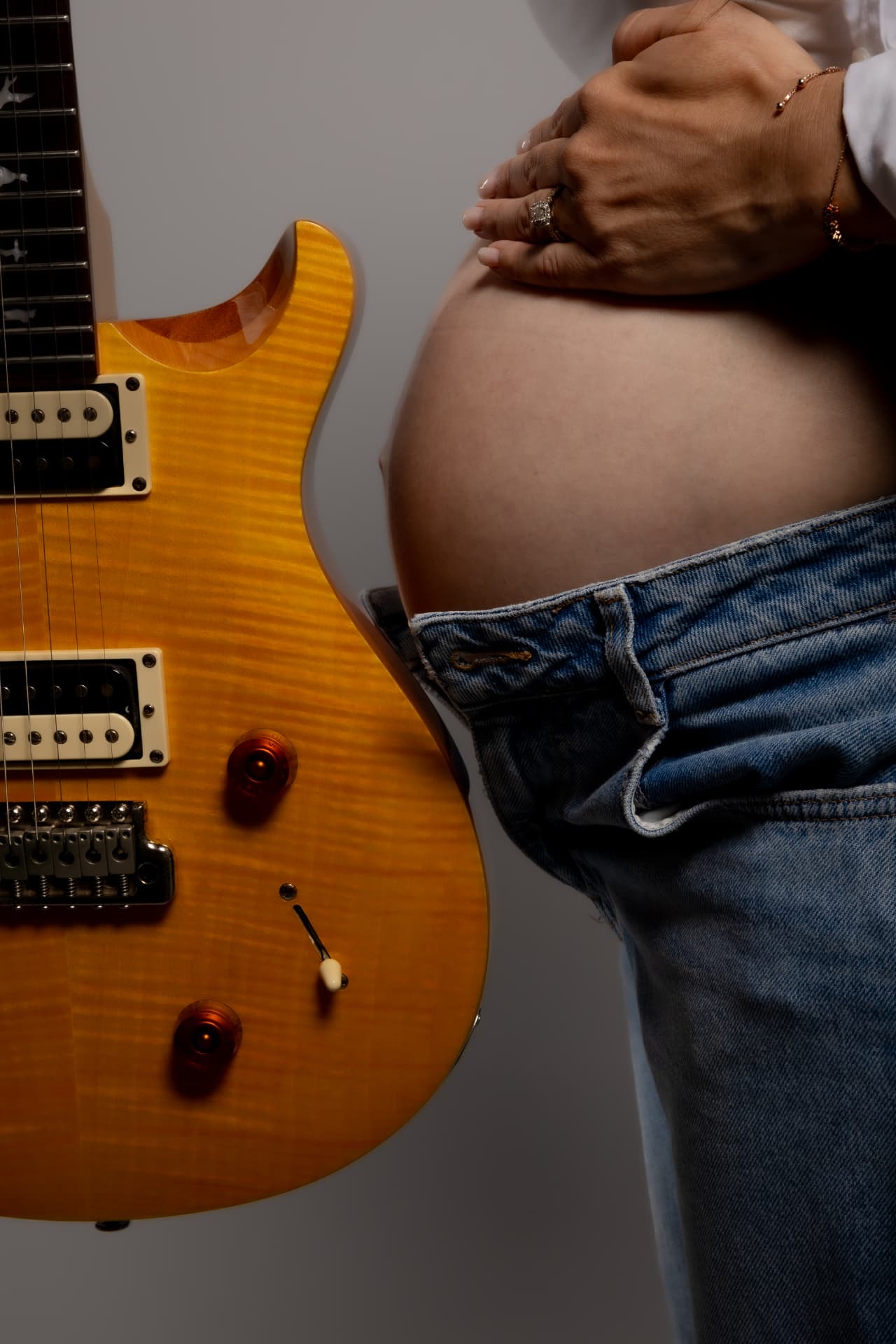 Detalle de barriga de embarazo junto a guitarra eléctrica