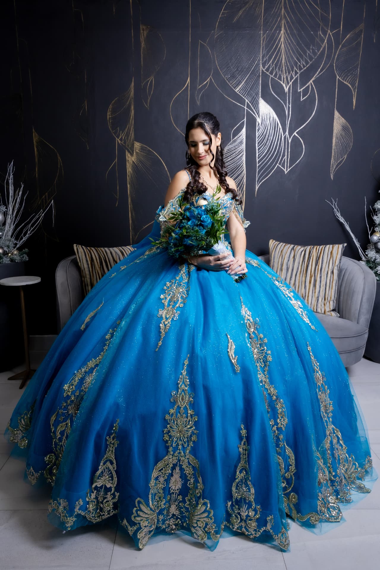 Quinceañera con vestido azul y detalles dorados en retrato de studio