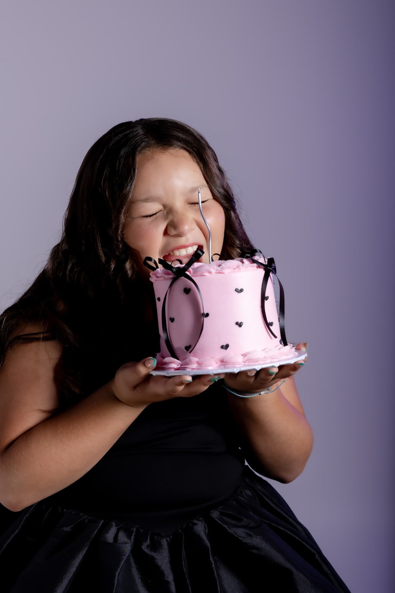 Niña feliz sosteniendo pastel rosa decorado con corazones